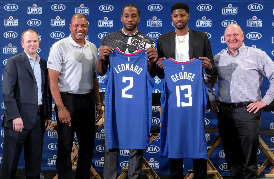 FILE - In this July 24, 2019, file photo, players Kawhi Leonard, center, and Paul George, second from right, hold their new team jerseys as they pose with Clippers president of basketball operations Lawrence Frank, left, head coach Doc Rivers, second from left, and team chairman Steve Ballmer, right, during a news conference in Los Angeles. The NBA's balance of power has shifted to the Clippers, who have never advanced beyond the second round let alone won a championship. All that is expected to change behind Leonard and George, both regarded as two of the best two-way players in the league. (AP Photo/Ringo H.W. Chiu, File)