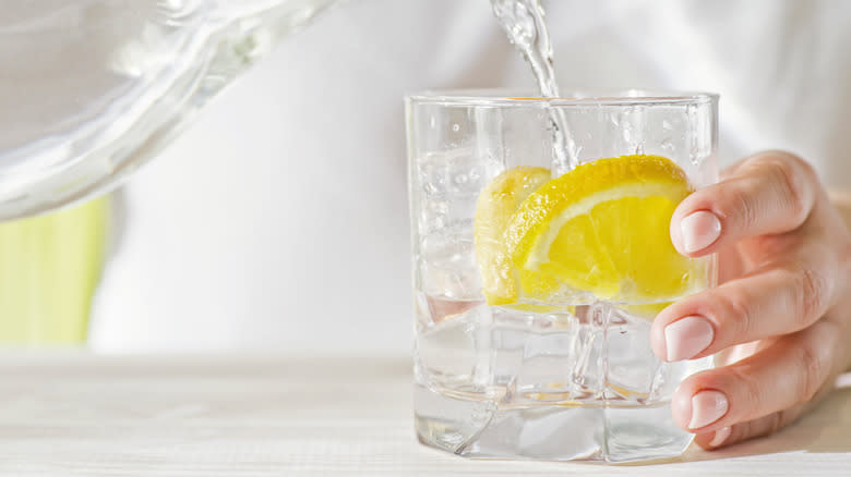 pouring water into glass with lemon