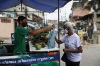 A woman buys vegetables from the Horta de Manguinhos in the Manguinhos favela in Rio de Janeiro