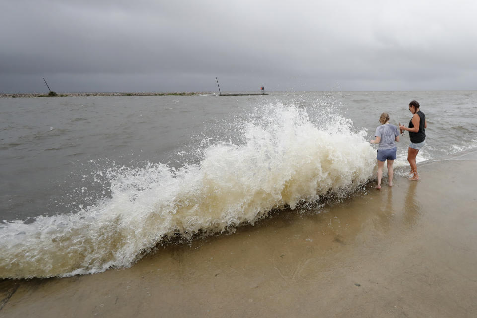 Erin Shaw, left, and Brittany Schanzbach stand near crashing waves near the seawall of Lake Pontchartrain from a storm surge in New Orleans, Sunday, June 7, 2020, as Tropical Storm Cristobal approaches the Louisiana Coast. (AP Photo/Gerald Herbert)