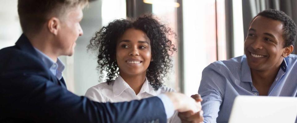 Happy clients african american couple handshake and sign mortgage contract