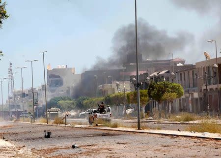 Fighters ride a pickup truck as smoke rises during a battle with Islamic State fighters in neighborhood Number Two in Sirte, Libya August 16, 2016. REUTERS/Ismail Zitouny