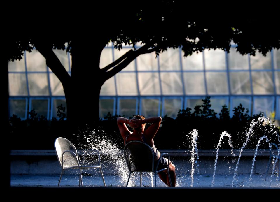 A person sits beside fountains at the Myriad Botanical Gardens.