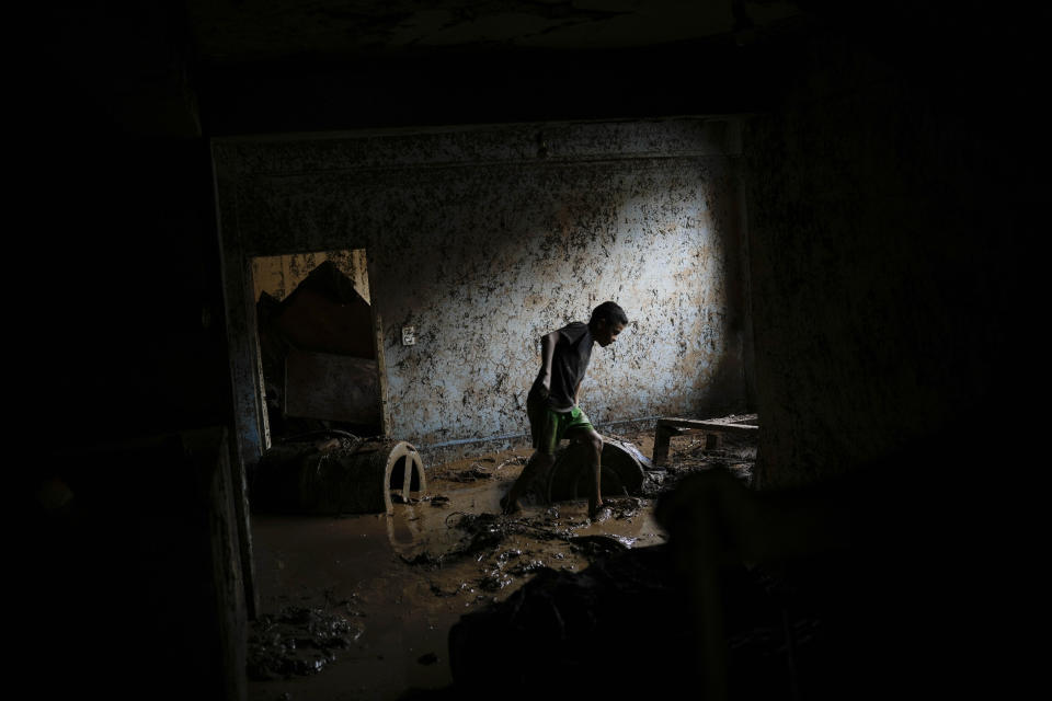 Emanuel Sanchez works to remove mud from inside his flooded home in Las Tejerias, Venezuela, on Oct. 9, 2022. (AP Photo/Matias Delacroix)