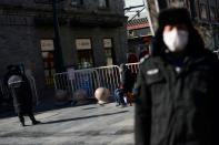 Un guardia de seguridad con una mascarilal es visto frente a una entrada de la calle peatonal Qianmen a un hutong, después de un brote del nuevo coronavirus en el país, en Pekín, China 18 de febrero de 2020