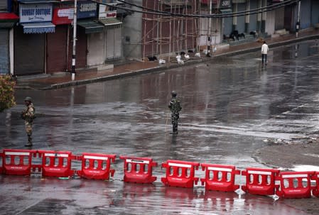 Indian security force personnel stand guard in a deserted street during restrictions after the government scrapped special status for Kashmir, in Srinagar