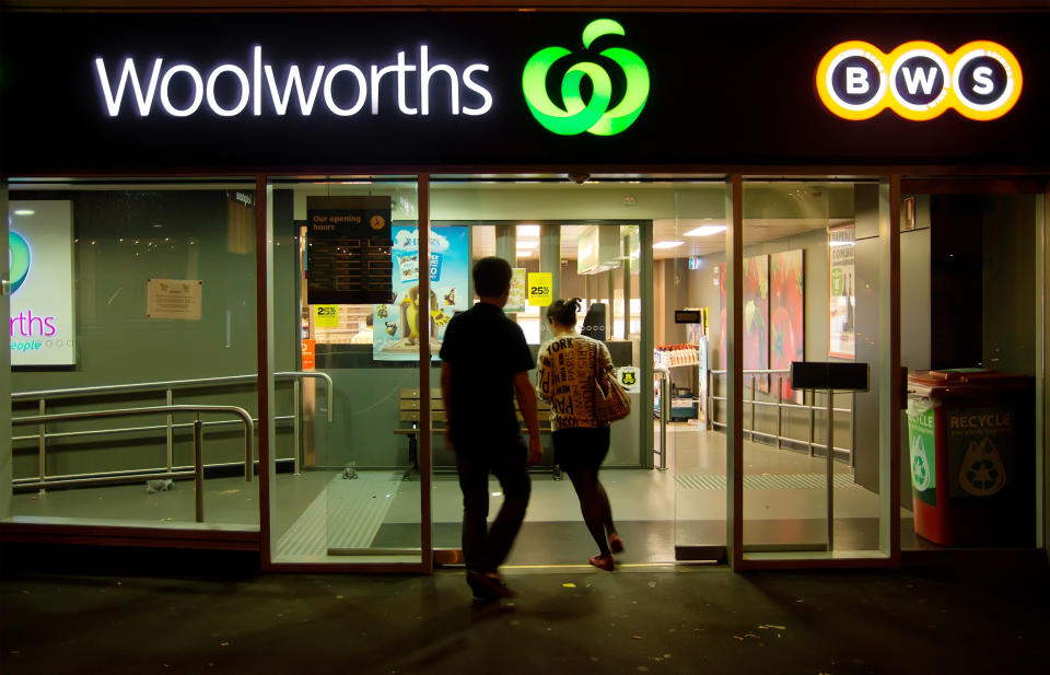 Sydney, Australia - March 22, 2014: A man and woman enter a Woolworths supermarket and BWS outlet on Macleay St, Potts Point, at night. Woolworths is the largest supermarket chain in Australia, while BWS are liquor stores owned by Woolworths.