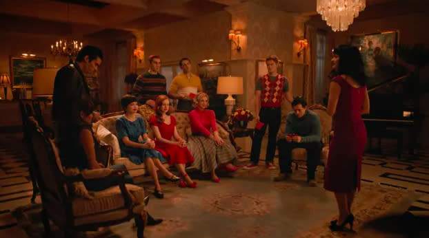 The main characters of Riverdale sit and stand in Veronica's huge and fancy apartment. They are dressed in traditional 1950s apparel.