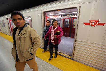 Honduran migrants Raul Contreras (L), his mother Daysi Alas (R) and step-father Ananin Cruz, who are seeking refugee status in Canada, exit a subway car while travelling to attend a church service held in Spanish in Toronto, Ontario, Canada April 8, 2017. Picture taken April 8, 2017. REUTERS/Chris Helgren