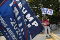 Supporters of President Donald Trump and former Vice President Joe Biden (obscured) wave flags and hand out information to arriving voters outside an early voting polling station in West Palm Beach, Fla., Friday, Oct. 30, 2020.(AP Photo/Rebecca Blackwell)