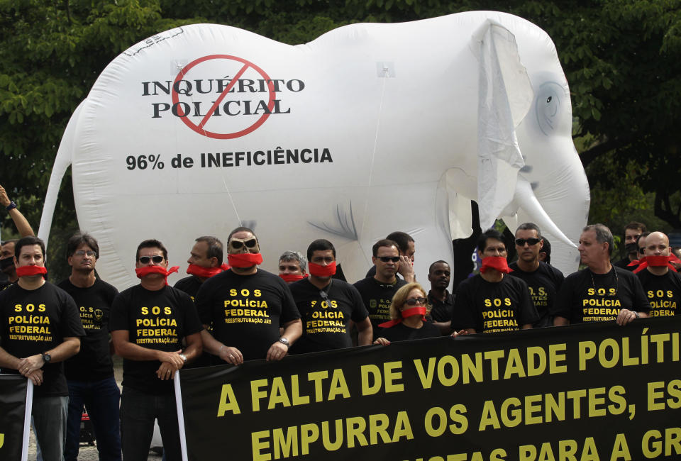 Federal police protest for better labor conditions outside the venue where Brazil's coach is announcing his squad for the upcoming World Cup where they placed a white elephant doll symbolizing public waste that reads in Portuguese "No police investigation. 96% inefficiency" in Rio de Janeiro, Brazil, Wednesday, May 7, 2014. Federal police are threatening to go on strike during the international soccer tournament if their demands are not met. (AP Photo/Silvia Izquierdo)