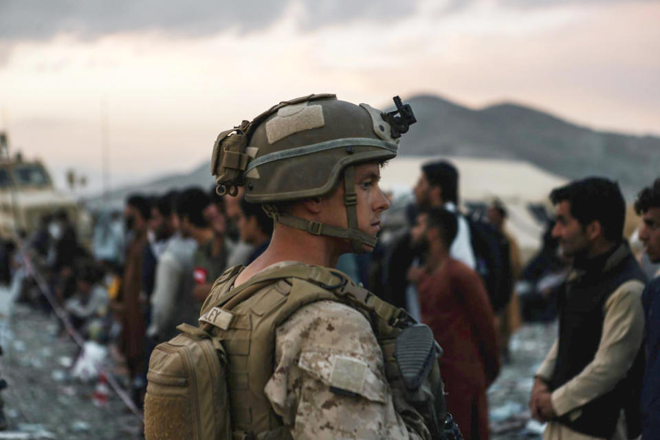 In this image provided by the U.S. Marines, a Marine assigned to Special Purpose Marine Air Ground Task Force-Crisis Response-Central Command assists evacuees during an evacuation at Hamid Karzai International Airport in Kabul, Afghanistan, Friday, Aug. 20, 2021. (Sgt. Isaiah Campbell/U.S. Marine Corps via AP)