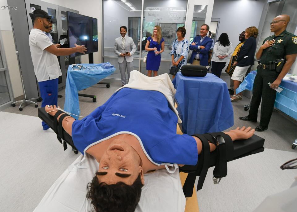CSE Apollo adult patient simulator is seen in the foreground as Indian River State College student Michael Otero (left) explains the new technology to guests touring the surgical suite during IRSC’s grand opening of their School of Nursing expansion on Tuesday, Aug. 8, 2023, in Port St. Lucie. "It's going to be helpful because it gives you a sense of what's going on inside the human body” Otero said.