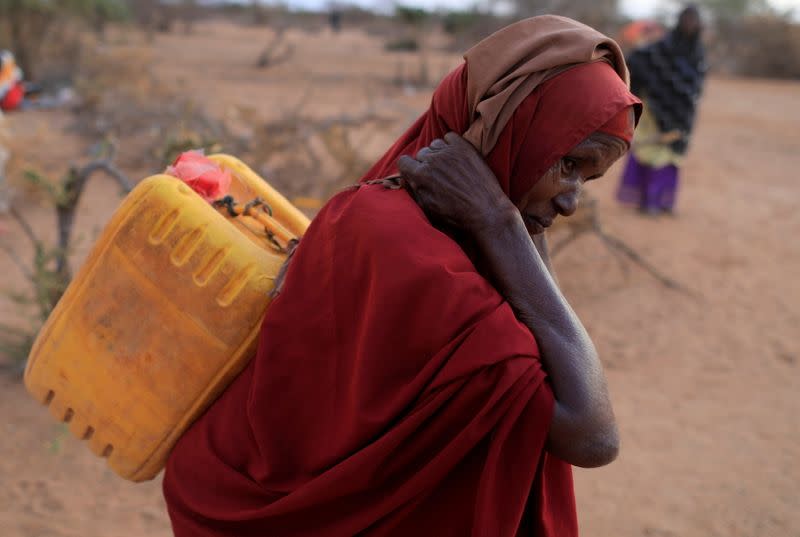 FILE PHOTO: An internally displaced woman from drought hit area carries a jerrycan of water as she walks towards her shelter at a makeshift settlement area in Dollow