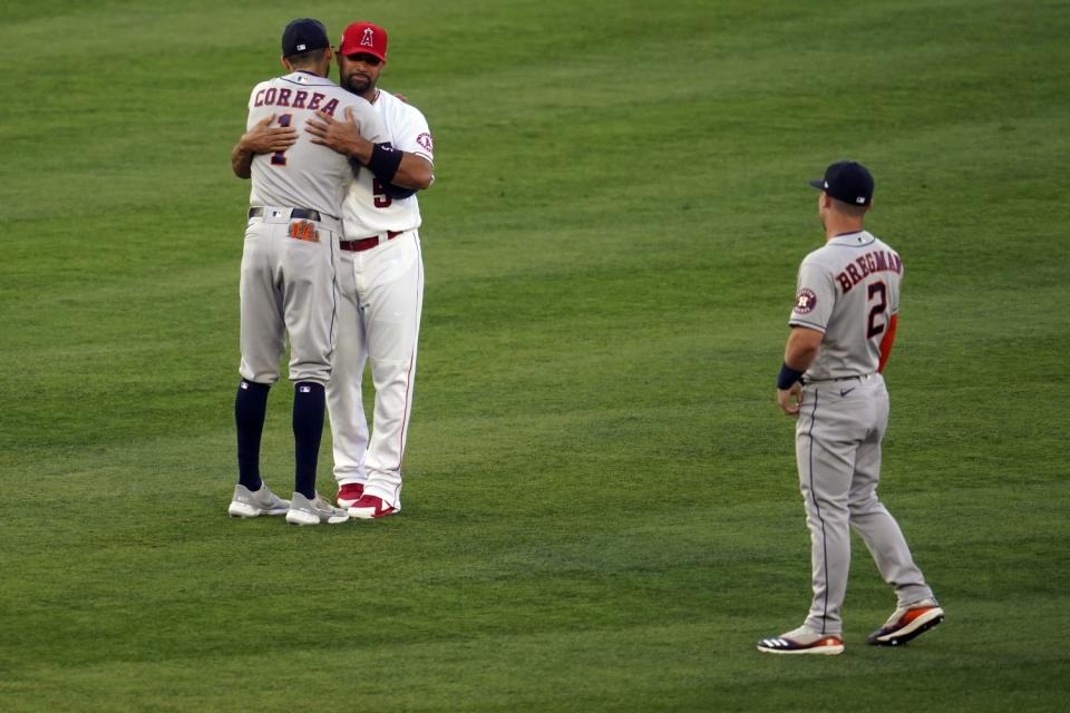 Albert Pujols hugs Carlos Correa with Alex Bregman nearby.