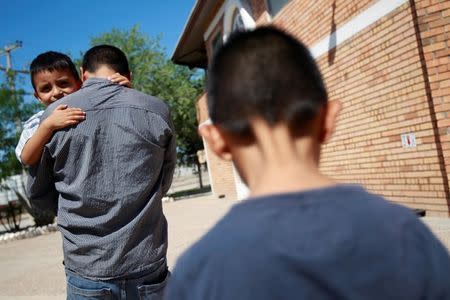 Salvadoran migrant Epigmenio Centeno carries his three-year old son Steven Atonay, as his nine-year son old Axel Jaret follows, outside the shelter House of the Migrant, after Epigmenio decided to stay with his children in Mexico due to U.S. President Donald Trump's policy that separates immigrant children from their parents, in Ciudad Juarez, Mexico June 19, 2018. REUTERS/Jose Luis Gonzalez