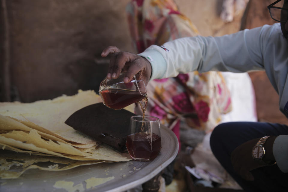 A Sudanese Man pours a glass of Helo Murr, a Ramadan drink made with dried corn and spices which is then dipped in water,, in Khartoum, Sudan, Wednesday, March. 22, 2023, ahead of the Muslim holy fasting month of Ramadan. (AP Photo/Marwan Ali)