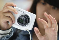 BERLIN, GERMANY - AUGUST 30: A visitor tries out the new Samsung Galaxy Camera, which combines a smartphone and a digital camera with a zoom lens, during a press day at the Samsung stand at the IFA 2012 consumer electronics trade fair on August 30, 2012 in Berlin, Germany. IFA 2012 will be open to the public from August 31 through September 5. (Photo by Sean Gallup/Getty Images)