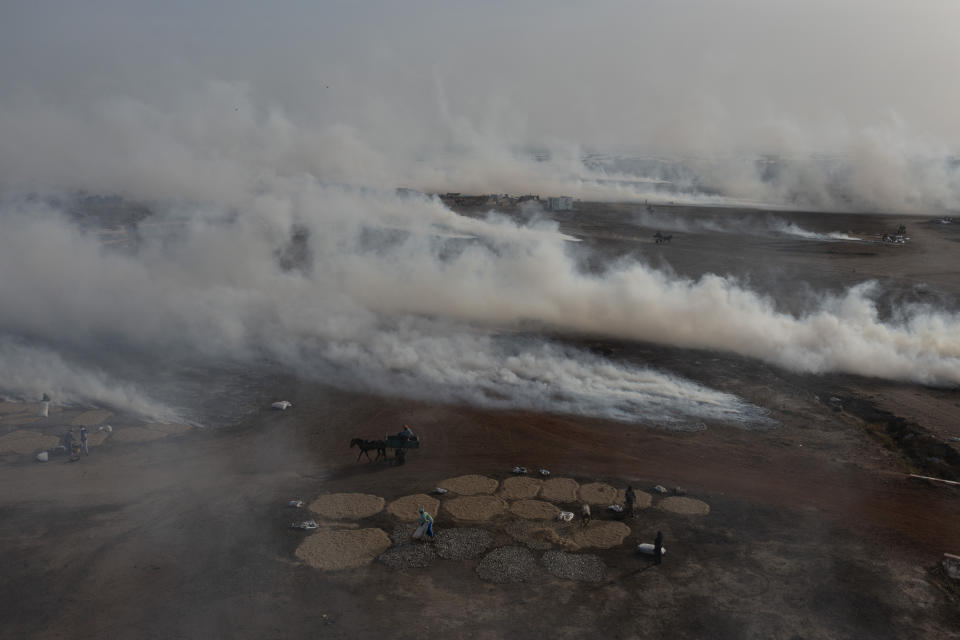 Plumes of smoke from fish processing rise above Bargny beach, some 35 kilometers (22 miles) east of Dakar, Senegal, Wednesday April 21, 2021. In Bargny and other coastal villages of Senegal, traditional fishing and processing of the catch is a livelihood and a pride. Methods have been passed down through generations. Women work as processors — drying, smoking, salting and fermenting the catch brought home by men (AP Photo/Leo Correa)