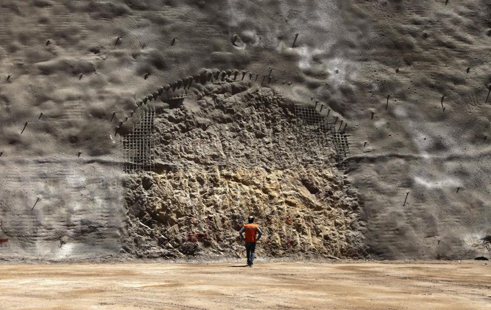 In this Sept. 25, 2012 photo, a worker from the National Copper Mine Corporation, or Codelco, looks at the area where a new tunnel is marked to be drilled at the Chuquicamata copper mine in the Atacama desert in northern Chile. Experts say that by 2019 the Chuquicamata copper mine will be unprofitable, so state-owned mining company Codelco is trying to head off closure by converting the open pit into the world's largest underground mine. Codelco believes the mine still has much more to give, with reserves equal to about 60 percent of all the copper exploited in the mine's history still buried deep beneath the crater. (AP Photo/Jorge Saenz)