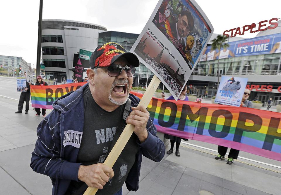 Dave Lara, of Los Angeles, joins demonstrators from a coalition of gay rights organizations, religious and political groups protest the treatment of gays in Russia, whose coastal city of Sochi hosts the 22nd Olympic Winter Games, outside the final stop of the "Road to Sochi," a traveling exhibit hosted by the U.S. Olympic Committee, at LALive in downtown Los Angeles Friday, Feb. 7, 2014. (AP Photo/Reed Saxon)