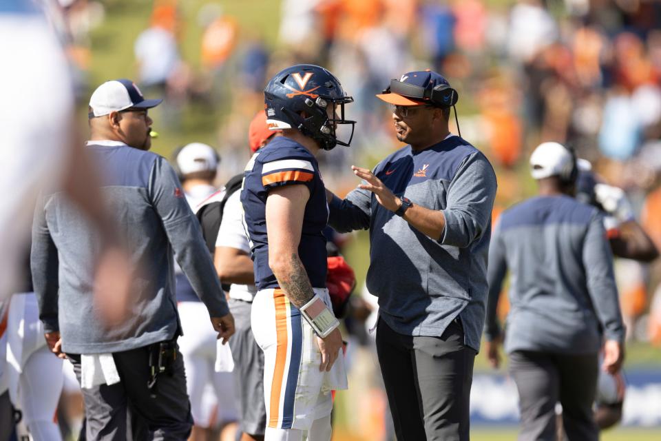 Virginia quarterback Brennan Armstrong, left, listens to head coach Tony Elliott, right, during an NCAA college football game against Louisville in Charlottesville, Va., Saturday, Oct. 8, 2022. (Mike Kropf/The Daily Progress via AP)