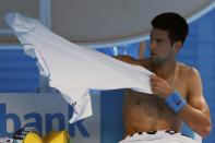 Novak Djokovic of Serbia puts on a new shirt during his men's singles second round match against Andrey Kuznetsov of Russia at the Australian Open 2015 tennis tournament in Melbourne January 22, 2015. REUTERS/Issei Kato (AUSTRALIA - Tags: SPORT TENNIS)