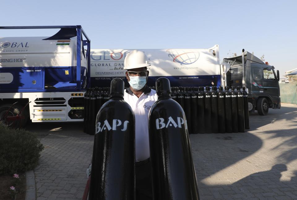 A volunteer carries containers of compressed oxygen before supplies are shipped to India, in Jebel Ali Free Zone, Dubai, United Arab Emirates, Monday, May 10, 2021. Volunteers from the country's Hindu community gathered to haul hundreds of cylinders of liquid oxygen and massive containers of compressed oxygen onto a ship bound for India. (AP Photo/Kamran Jebreili)