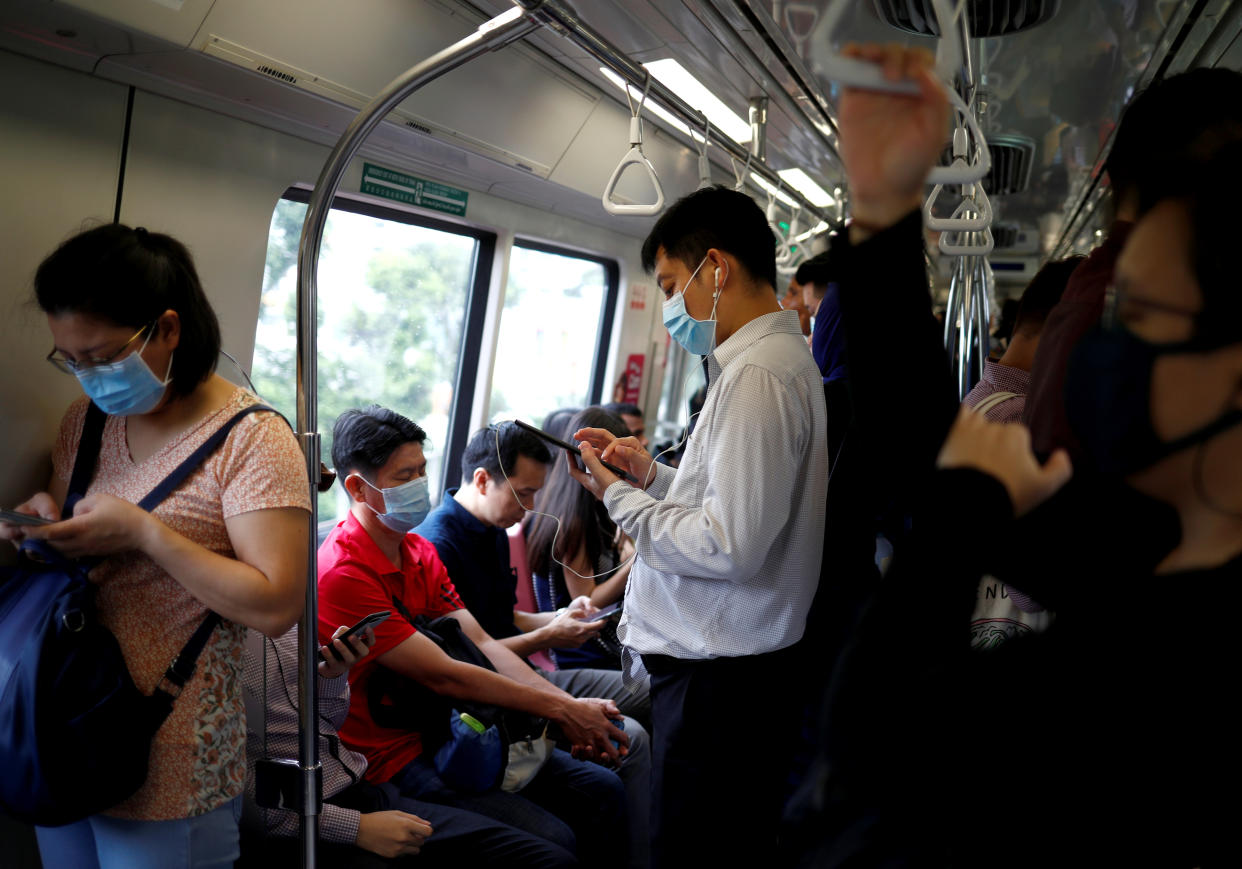 Commuters wearing masks in precaution of the coronavirus outbreak are pictured in a train during their morning commute in Singapore February 18, 2020. 