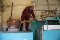 In this Saturday Sept. 8, 2018 photo, a worker checks on a brass still called a “karakeh” in Arabic, during a triple distillation process to make arak, Lebanon's national alcoholic drink, at the Doumaine de Tourelles winnery, in the town of Chtaura, east Lebanon. Homemade arak usually goes straight into gallon containers after distillation, ready for drinking. In commercial production, the arak sits in clay jugs for a year, making it smoother. (AP Photo/Hussein Malla)