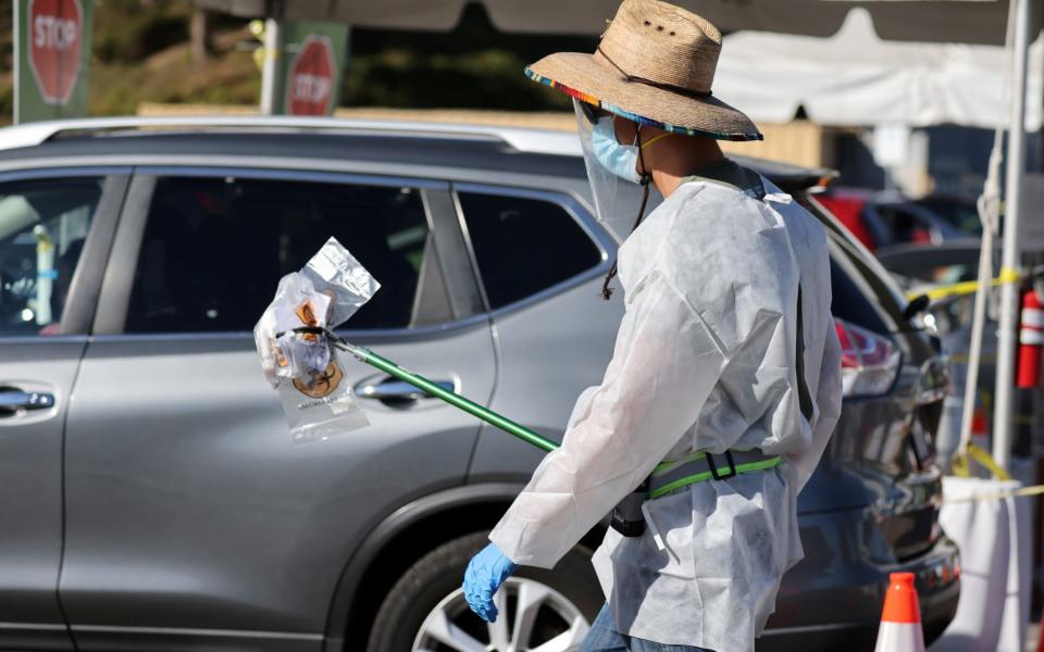 A worker carries novel coronavirus tests at a testing site in Los Angeles - LUCY NICHOLSON /REUTERS