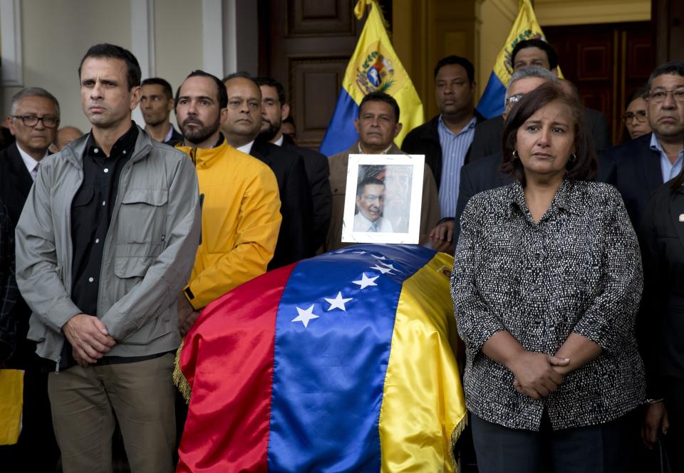 ARCHIVO - La legisladora Dinorah Figuera, a la derecha, junto al ataúd cubierto con una bandera que contiene los restos del activista opositor Fernando Albán durante una ceremonia solemne en la sede de la Asamblea Nacional en Caracas, Venezuela, el 9 de octubre de 2018. (AP Foto/Ariana Cubillos, Archivo)