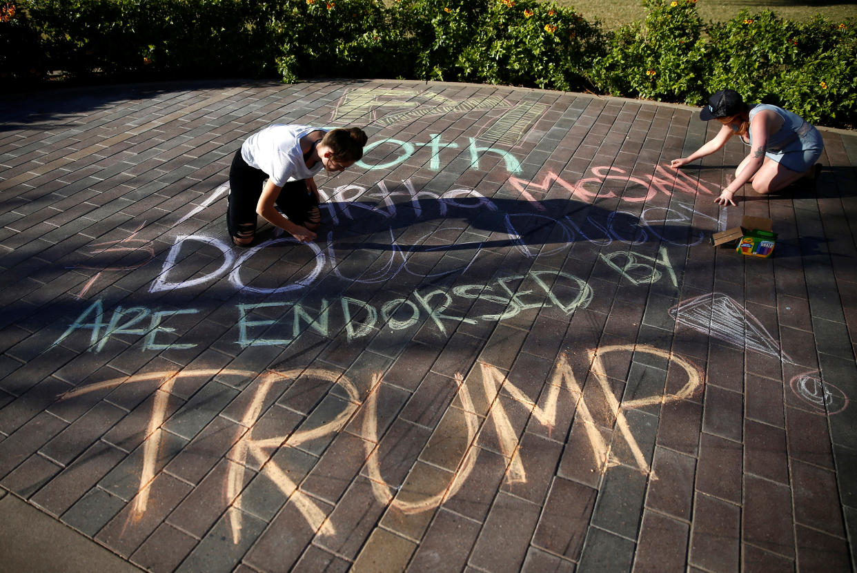 Darby Dunlop, left and Zoe Stein of NextGen America write a message that both Republican U.S. Senate candidate Rep. Martha McSally and Arizona Governor Doug Ducey are endorsed by Donald Trump next to a line of people waiting to vote at the ASU Palo Verde West polling station during the U.S. midterm elections in Tempe, Arizona, Nov, 6, 2018. (Photo: Lindsey Wasson / Reuters)