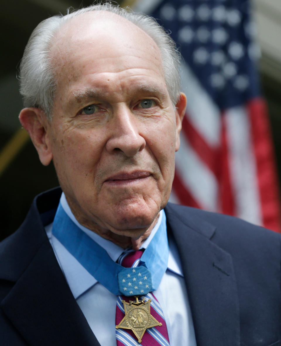 FILE - In this July 12, 2013, file photo, retired U.S. Navy Capt. Thomas Hudner wears the Medal of Honor awarded to him by President Truman, as he poses on the porch at his home in Concord, Mass. Hudner intentionally crashed his plane during the Korean War in 1950 to try to save his wingman Jesse Brown, whose plane had been shot down. A U.S. Navy destroyer named in Hudner's honor will be commissioned Saturday, Dec. 1, 2018, in Boston. He died, Nov. 13, 2017, at age 93. (AP Photo/Charles Krupa, File)