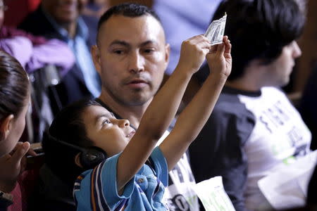 David Lazo, age 5, holds a dollar bill up at a Los Angeles City Council meeting that approved a proposal to increase the minimum wage to $15.00 per hour in Los Angeles, California June 3, 2015. REUTERS/Jonathan Alcorn