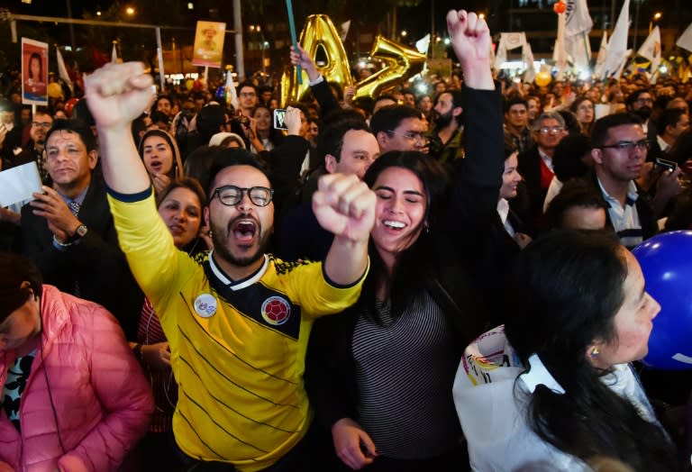 Colombians in Bogota celebrate on August 24, 2016 as they watch the signing of a peace agreement between the government and FARC guerrillas broadcast from Havana, Cuba