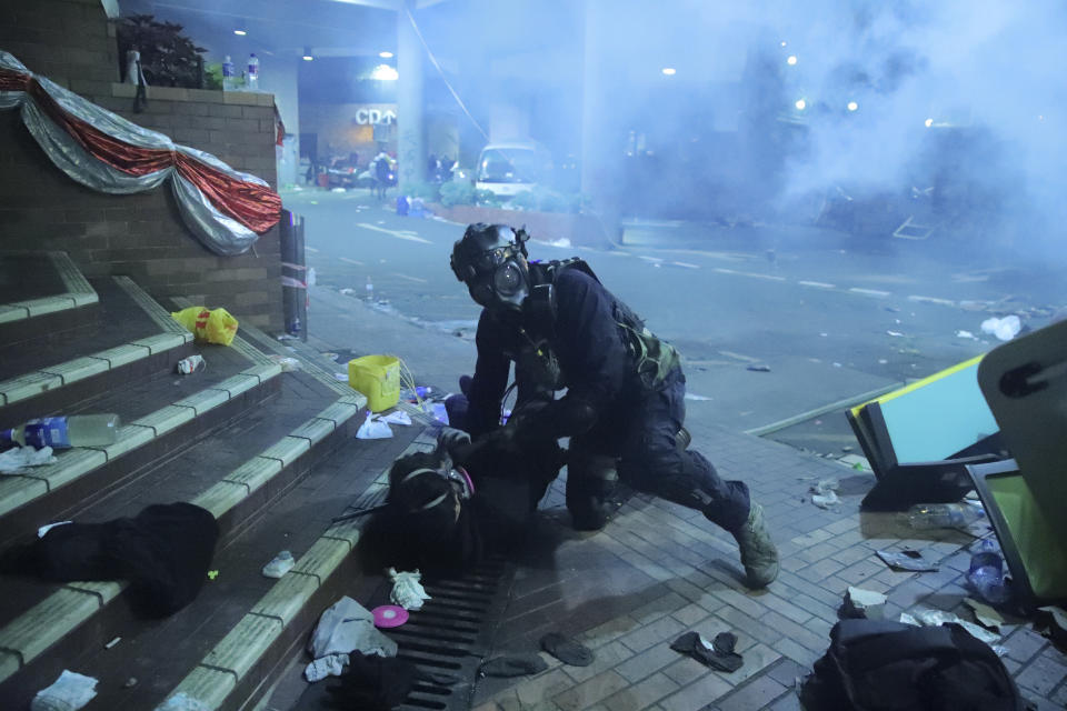 A policeman in riot gear detains a protester outside of Hong Kong Polytechnic University as police storm the campus in Hong Kong, early Monday, Nov. 18, 2019. Fiery explosions were seen early Monday as Hong Kong police stormed into a university held by protesters after an all-night standoff. (AP Photo/Kin Cheung)