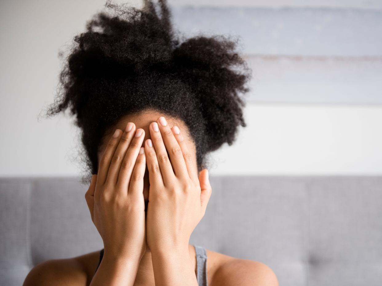 African American woman covering face with hands