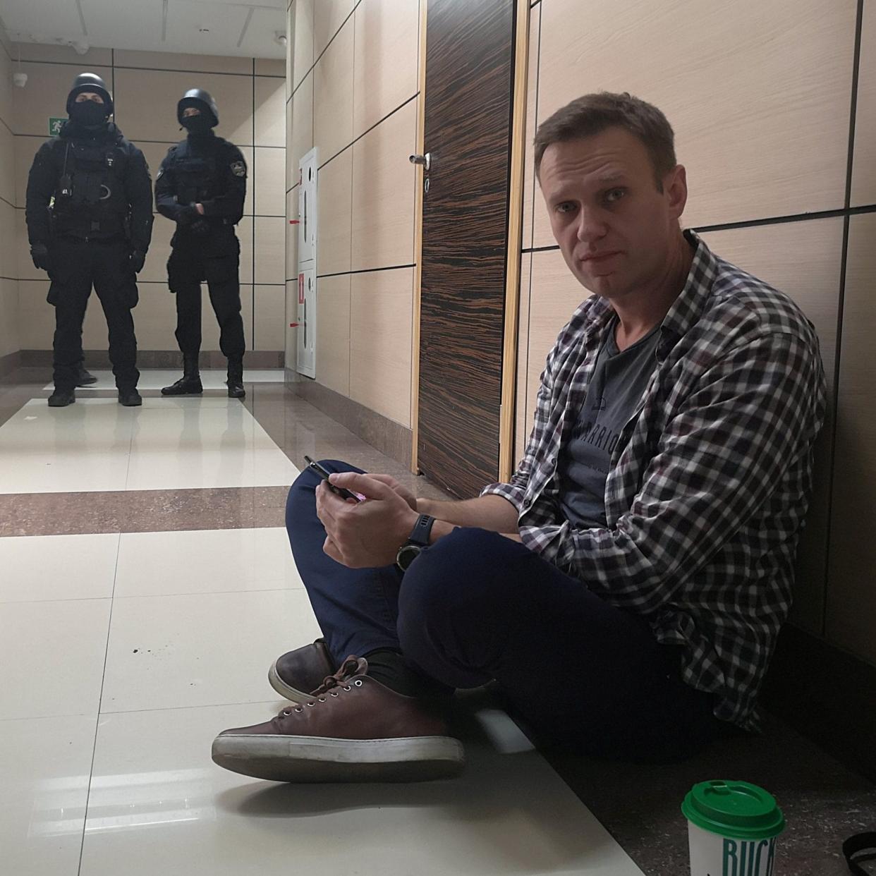 Russian opposition politician Navalny sits on the floor during a police raid of his office in Moscow - VIA REUTERS