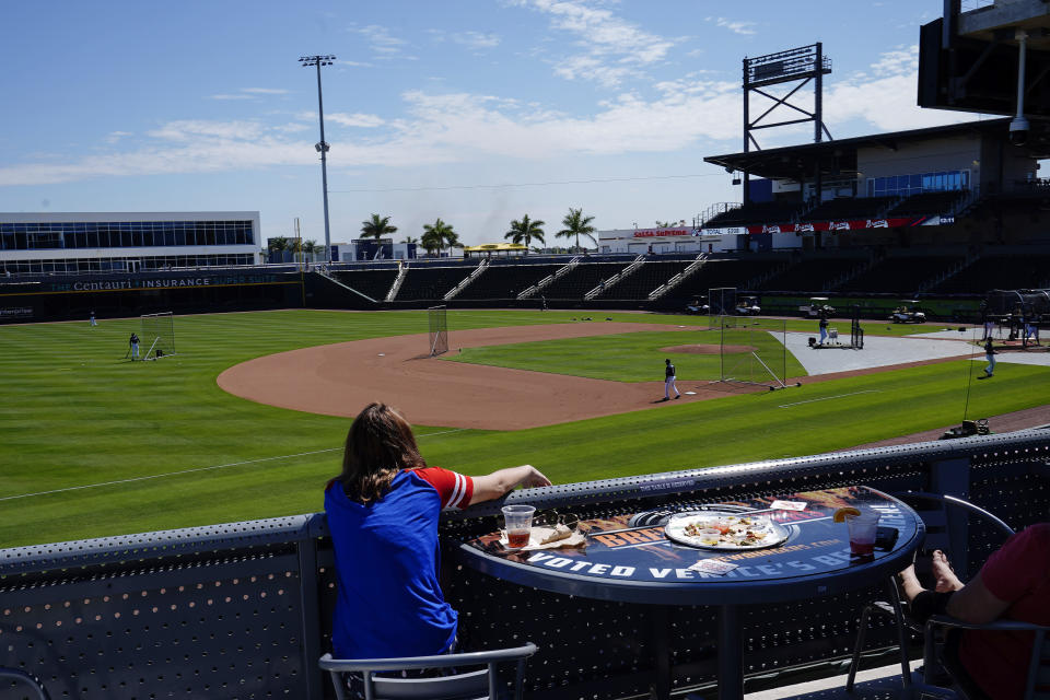 A fan watches the Atlanta Braves take batting practice during spring training baseball practice on Tuesday, Feb. 23, 2021, in North Port, Fla. (AP Photo/Brynn Anderson)