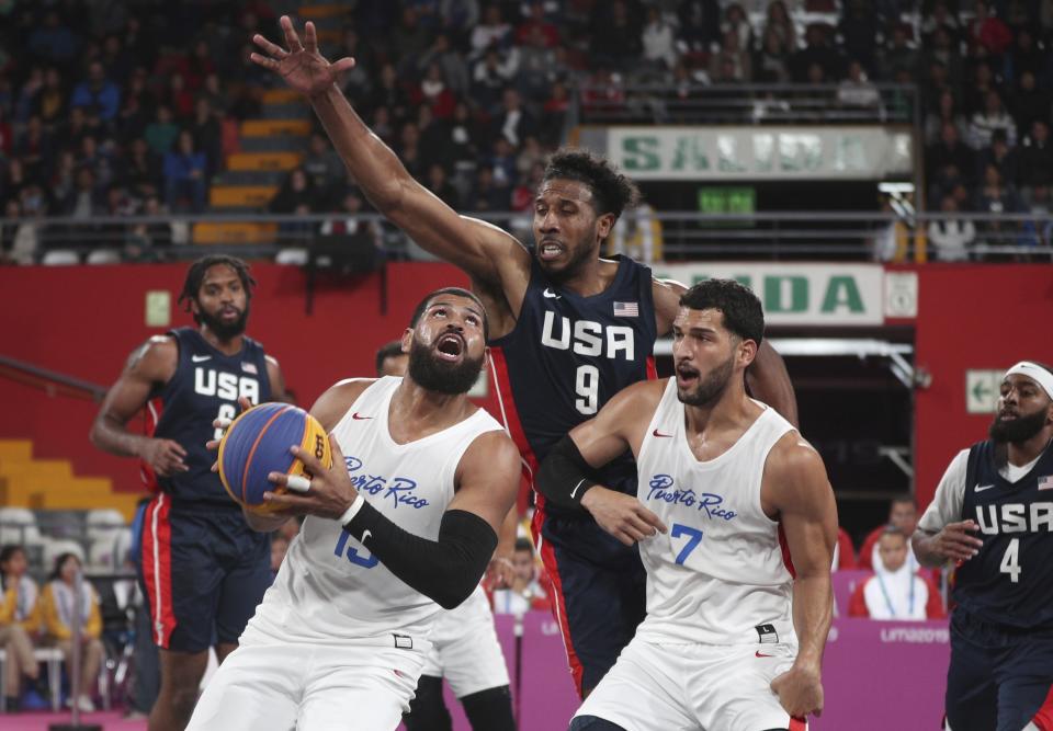 FILE - Kareem Maddox of the U.S., center, tries to block the shot of Angel Matias of Puerto Rico, left, as Josue Erazo looks on during the men's basketball 3x3 final match at the Pan American Games in Lima, Peru, Monday, July 29, 2019. USA Basketball announced its men’s 3x3 roster for the Paris Games on Tuesday, March 26, 2024, going with the same foursome that won a silver medal at the World Cup and gold at the Pan American Games last year.(AP Photo/Martin Mejia, File)