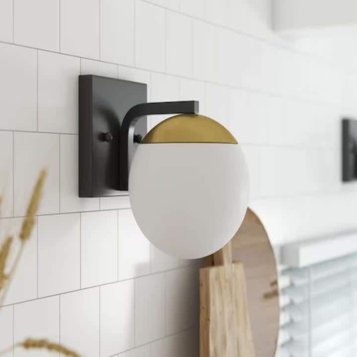 a globe sconce on a white tile wall