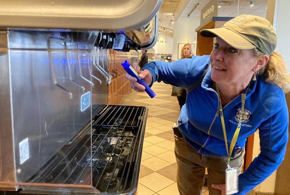 Lisa Susann, an environmental protection specialist with the Erie County Department of Health, uses a flashlight to inspect soda nozzles at Panera Bread, 2501 W. 12th St., on April 18.