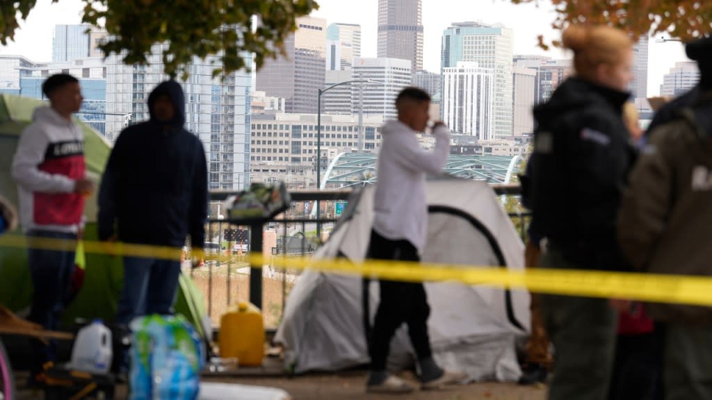 Occupants wait to see how police officers work during a city-sponsored sweep of a migrants’ encampment overlooking the Denver city skyline on Diamond Hill on Nov. 1. The sweep was just one of several staged in various locations across the Mile High City. (Photo: David Zalubowski/AP)