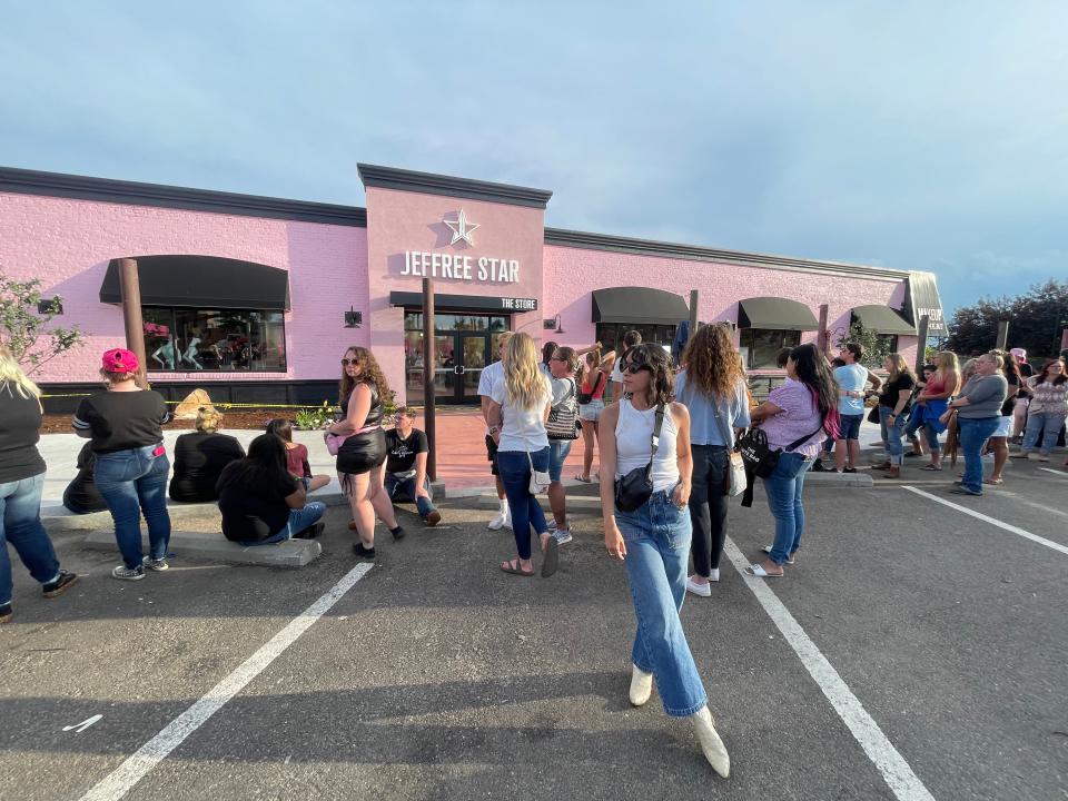 a line of people waiting in front of the pink Jeffree store star building