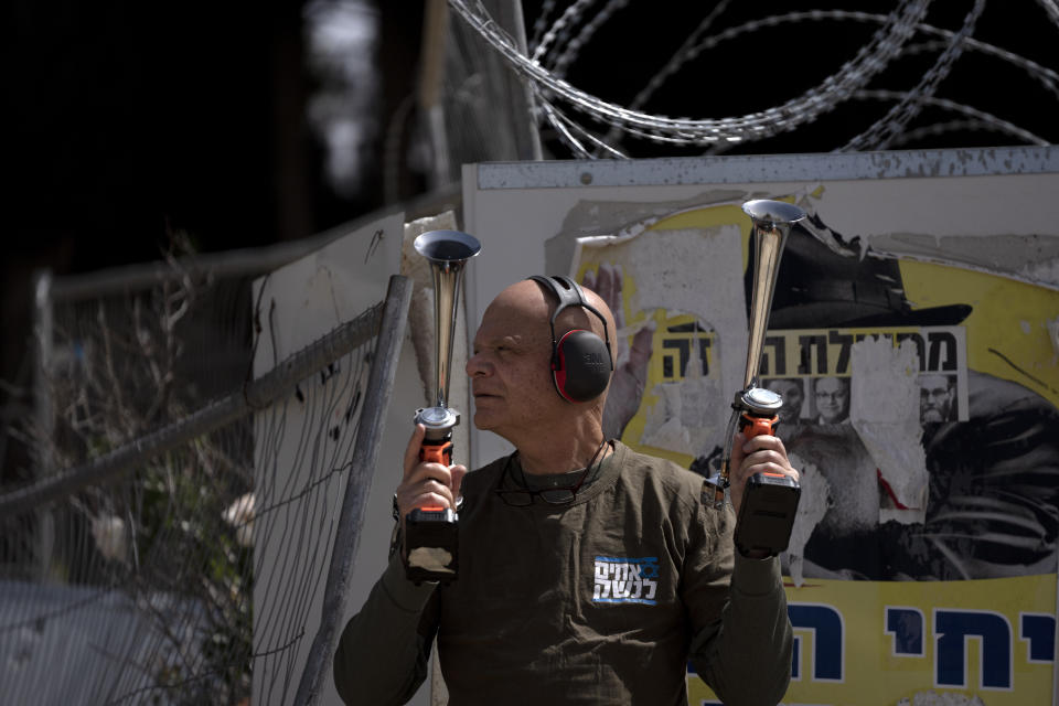 A members of Brothers and Sisters in Arms uses two horns during a protest against Israel's exemptions for ultra-Orthodox Jews from mandatory military service, near the Prime Minister's office in Jerusalem, Tuesday, March 26, 2024. (AP Photo/Maya Alleruzzo)