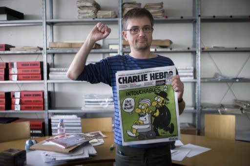 French satirical weekly Charlie Hebdo's publisher, known only as Charb, clenches his fist as he presents Wednesday's issue of the magazine to journalists in Paris. The magazine contains nude cartoons of the Prophet Mohammed