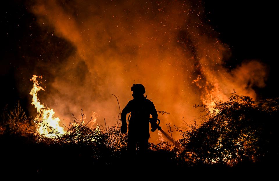 TOPSHOT - A firefighter tackles a forest fire around the village of Eiriz in Baiao, north of Portugal, on July 15, 2022. (Photo by Patricia De Melo MOREIRA / AFP) (Photo by PATRICIA DE MELO MOREIRA/AFP via Getty Images)