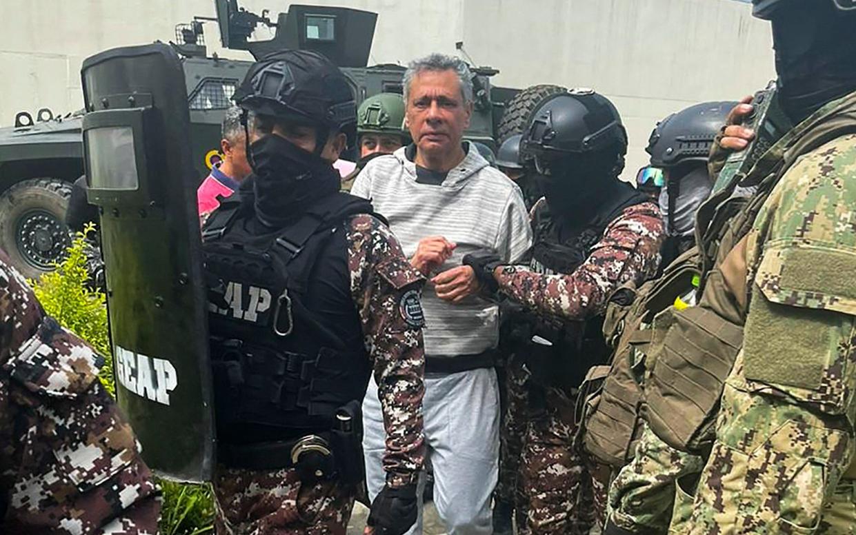 A handcuffed and worried-looking Jorge Glas is surrounded by police in riot gear