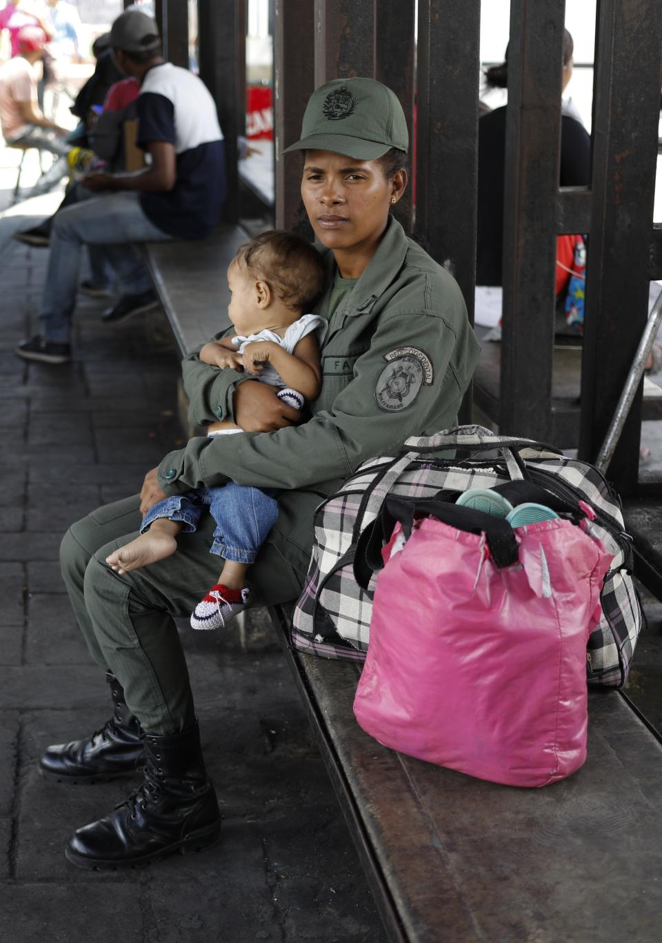 A member of the Bolivarian Army cradles her son at a bus terminal in Caracas, Venezuela, Wednesday, Feb. 19, 2020. The debate over fresh U.S. sanctions aimed at forcing out Venezuela's Nicolás Maduro played out Wednesday across the crisis-stricken South American nation. Families have been split up with at least 4.5 million Venezuelans fleeing crumbling public services. (AP Photo/Ariana Cubillos)